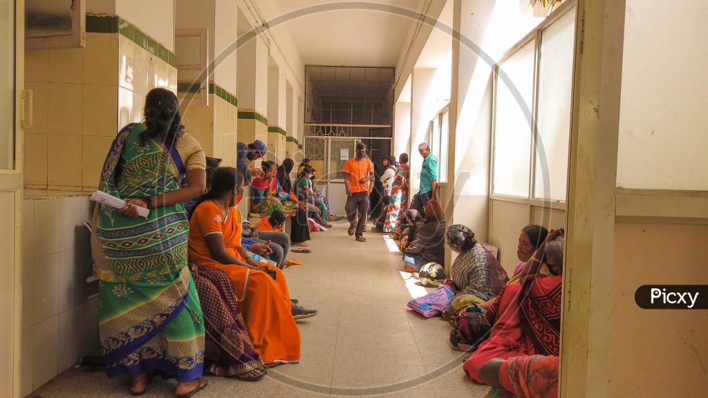 Patients and relatives waiting along a corridor inside a crowded public hospital in India.