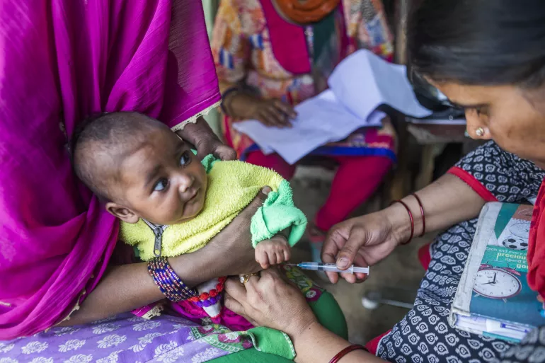 Health worker vaccinating a baby during a community immunisation programme in India.